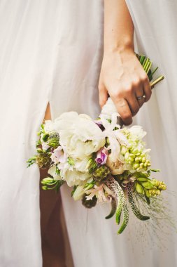 Bright wedding bouquet in hands of the bride.