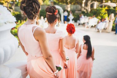 Bridesmaids with flowers stand at the wedding ceremony.