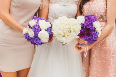 Bride with bridesmaids with flowers stand in a row.