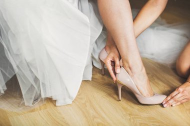 Bride in the morning during wedding preparations. Bridesmaid helping with shoes