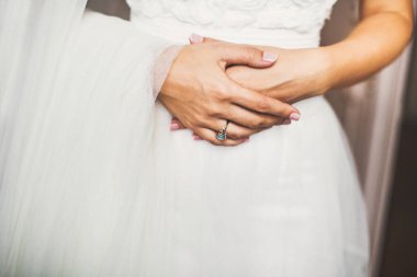 Engagement ring on bride's finger during wedding preparations.