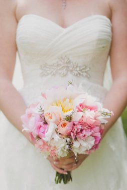 Bright wedding bouquet in hands of the bride.