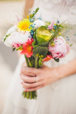 Bright wedding bouquet in hands of the bride.