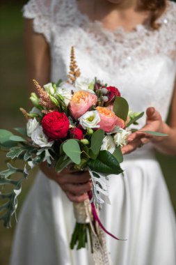 Bright wedding bouquet in hands of the bride.