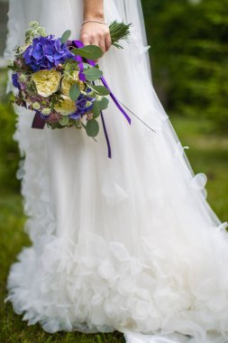 Bright wedding bouquet in hands of the bride.