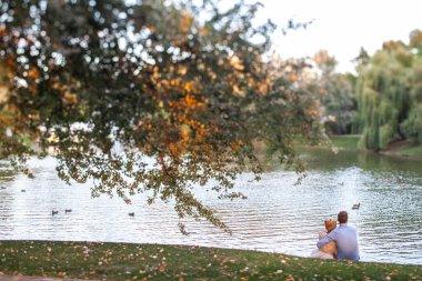 Bride and groom on their wedding day. Newlyweds sit in an embrace near the lake