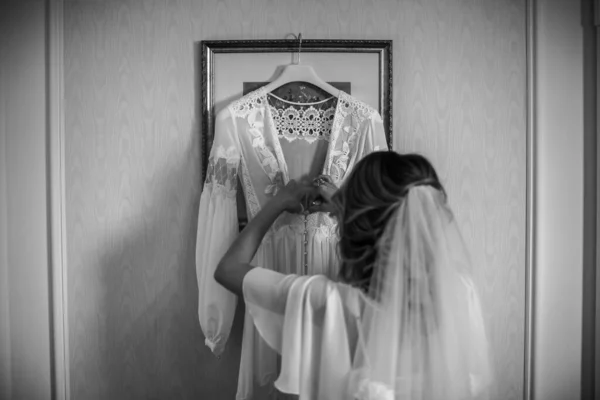 Bride in the morning during wedding preparations. The bride takes the dress