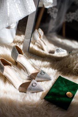 Two golden rings lie on wedding shoes.