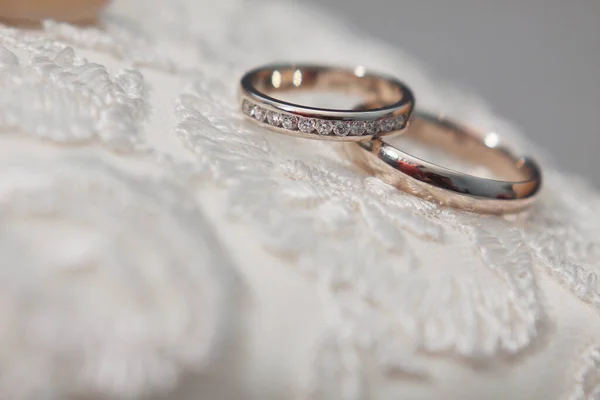 Two rings lie on a wedding dress.