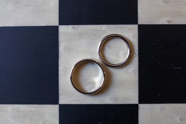 Two Wedding Rings Lie Chessboard — Stockfoto