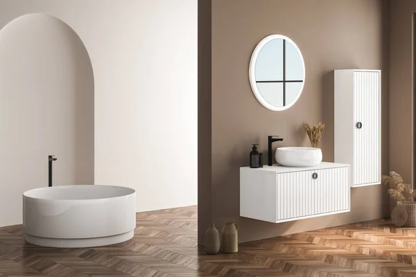 Modern bathroom interior with beige walls, white basin with oval mirror, bathtub and parquet floor. Minimalist beige bathroom with modern furniture. 3D rendering