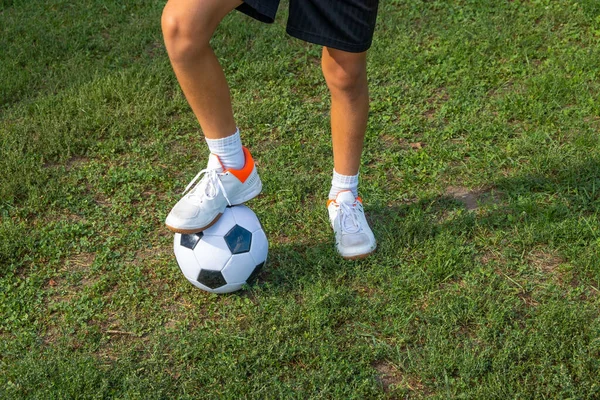 Junge Teenager legt sein Bein auf Ball auf Fußballplatz. — Stockfoto