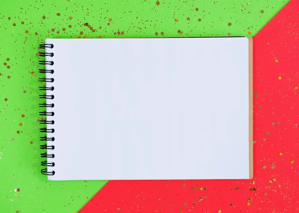 Libro de notas vacío maqueta con estrellas brillantes confeti sobre un fondo rojo y verde. — Foto de Stock