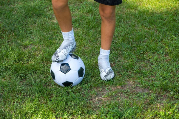 Menino adolescente coloca sua perna na bola no campo de futebol. — Fotografia de Stock