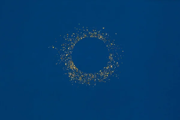 파란 배경에 빈 가운데로 반짝 이는 둥근 금빛 반짝 이는 물체. — 스톡 사진