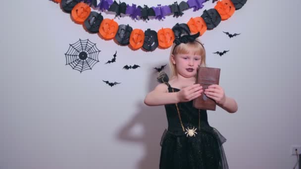 Kleines Mädchen im Hexenkostüm telefoniert mit Freunden, Verwandten und zeigt einen Luftkuss — Stockvideo