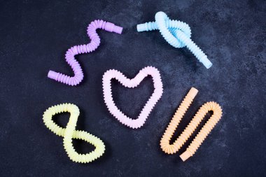 Siyah arka planda çok renkli parlak tüpler. Stres önleyici duyusal plastik oyuncak.