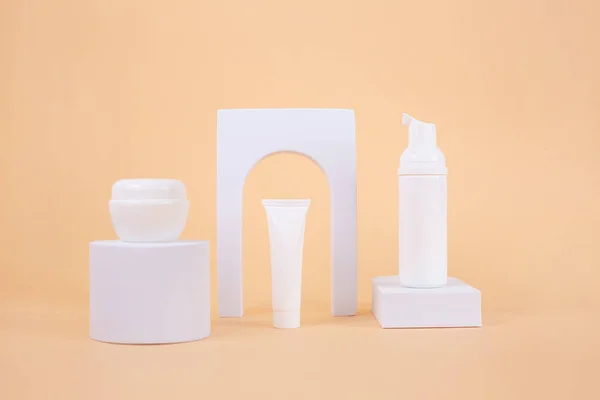 Set de Cremas Blancas tubo maqueta sobre podio blanco con arco sobre fondo beige. — Foto de Stock
