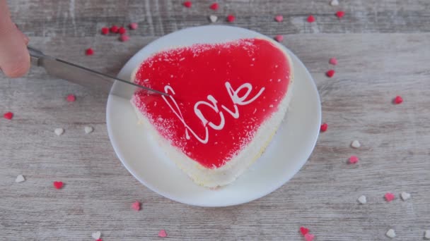 Las manos femeninas cortan un pedazo de pastel en forma de corazón. — Vídeos de Stock