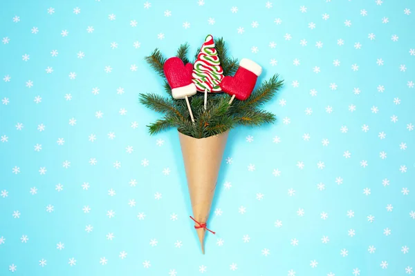 Dar zielony jodła w torbie papierowej rzemiosła z cukierki świąteczne na niebieskim tle. — Zdjęcie stockowe