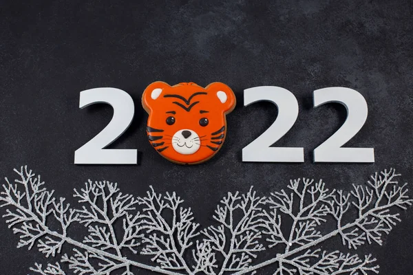 Número 2022 e biscoitos de gengibre na forma de tigre no fundo escuro. Fotografias De Stock Royalty-Free