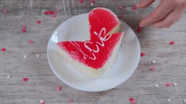 Kadın eli, kalp şeklinde bir parça kek kesiyor..