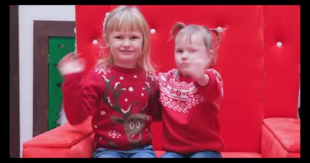 Kleine meisjes in kerst trui golven hand palm in hello gebaar verwelkomt iemand — Stockvideo
