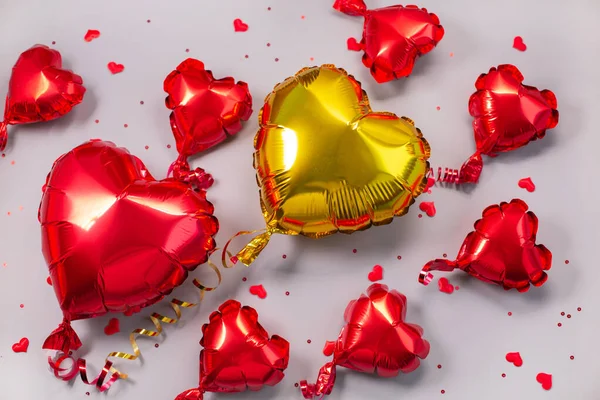 Rood en goud Luchtballonnen van hartvormige folie op grijze achtergrond. — Stockfoto