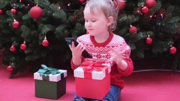 Klein meisje met behulp van smart phone praten met familie feliciteert vrolijk kerstfeest door videogesprek. — Stockvideo