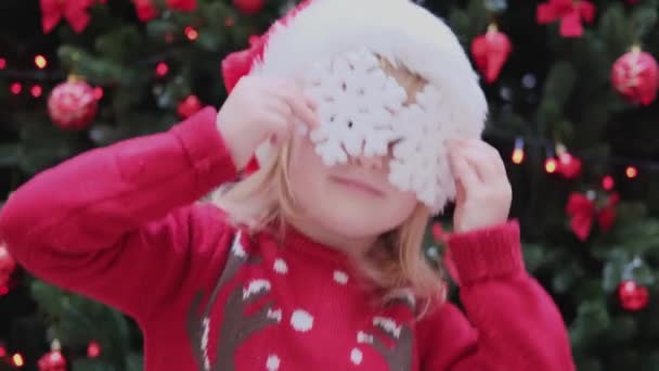 Lycklig liten flicka som har kul tittar in i kameran gör galna roliga ansikte med snöflingor på ögonen. — Stockvideo