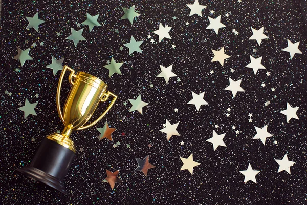 Una copa ganadora de oro con estrellas plateadas brilla sobre un fondo negro. Fotos de stock