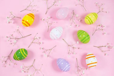 Pembe arka planda beyaz çigila ile renkli Paskalya yumurtaları.