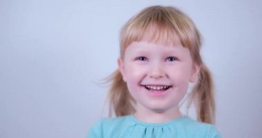 Kameraya bakıp gülümseyen küçük sarışın kız portresi. Mutlu Çocuk Gülüşü.