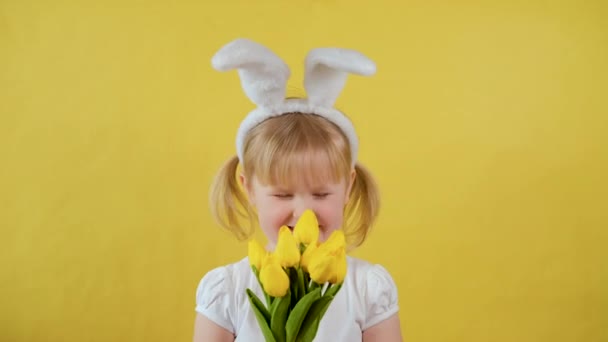 Весела блондинка маленька дівчинка тримає букет жовтих весняних квітів як подарунок . — стокове відео