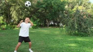 Çocuk futbol numaralarıyla pratik yapıyor ve antrenman yapıyor. Bacağa ve kafaya vuruyor..