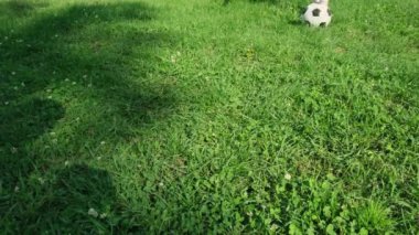 Genç çocuk dışarıda futbol oynuyor, top tekmeliyor ve yazın parkta koşuyor..