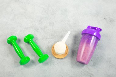 Titretici, dambıl ve ölçülen protein tozu gri beton arka planda