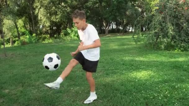 Niño practicando y entrenando en trucos de fútbol. patea la pelota en la pierna y la cabeza. — Vídeos de Stock