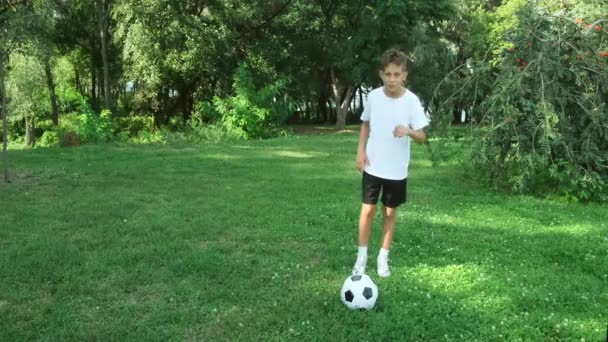 Tonårspojken spelar fotboll utomhus, sparkar boll på en park på sommaren. — Stockvideo