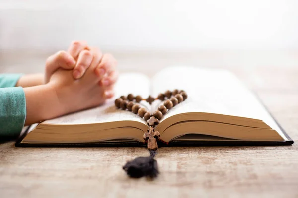 Manos de niño apretadas en oración sobre la Biblia abierta, Nuevo Testamento. Imagen de archivo