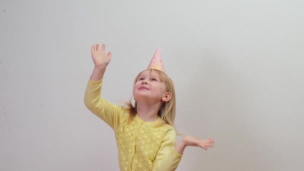 Niña feliz en sombrero de fiesta celebrando en fiesta de cumpleaños saltando con confeti — Vídeos de Stock