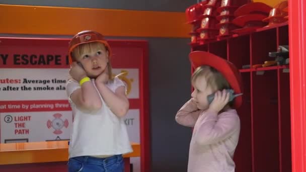 Dvě mladé dívky oblečené v helmách hasičů mluví na vysílačce — Stock video