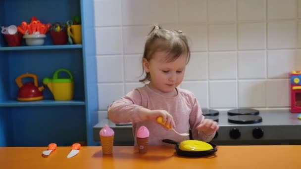 Szczęśliwa przedszkolanka bawiąca się kuchnią zabawki w centrum gier dla dzieci. Zabawa w pokoju dla dzieci. — Wideo stockowe