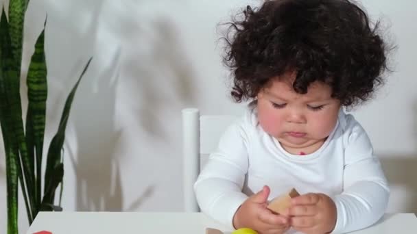 Mieszane wyścig maluch dziewczynka chłopiec siedzi przy stole i stosy drewniane zabawki — Wideo stockowe