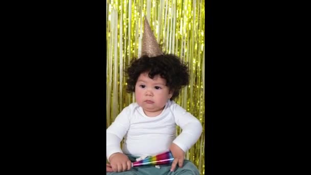 Happy Mixed-Race Kleinkind kleiner Junge sitzt auf dem Boden vor dem Hintergrund eines dekorierten Zimmers von seinem Geburtstag. — Stockvideo
