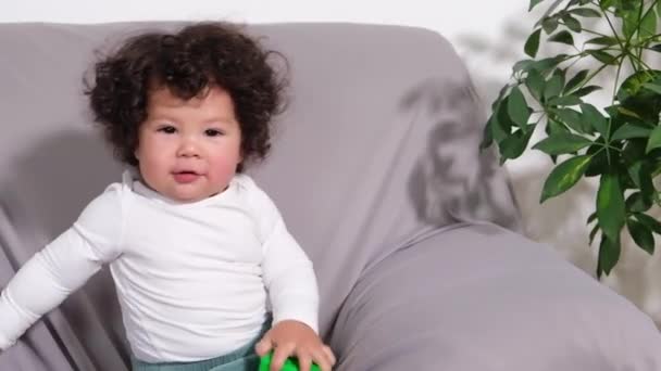 Cute dziecko chłopiec grać na kanapie w pokoju z zabawką w rękach. — Wideo stockowe