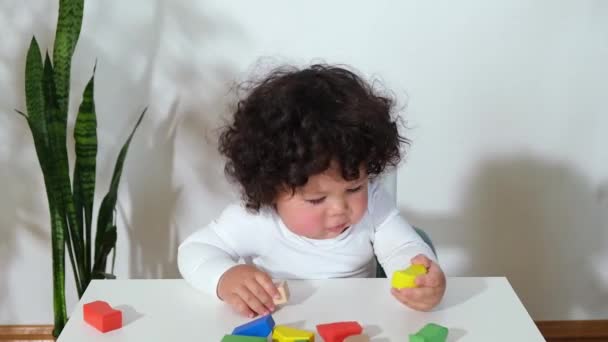 Mixed-race criança menino menina senta-se à mesa e empilha brinquedos de madeira — Vídeo de Stock
