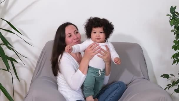 Happy cute little boy playing having fun with young adult mother on couch at home — Stock Video