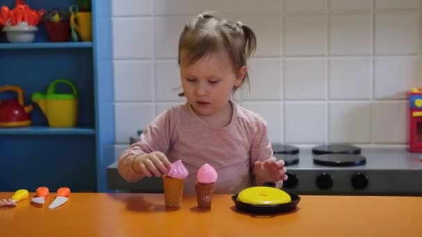 Щаслива дівчина дошкільного віку грає з іграшковою кухнею в дитячому ігровому центрі. Розваги в дитячій кімнаті . — стокове відео