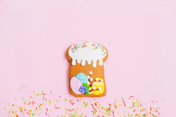 Pão de gengibre na forma de um bolo de Páscoa e polvilhas de cor doce no fundo rosa. — Fotografia de Stock